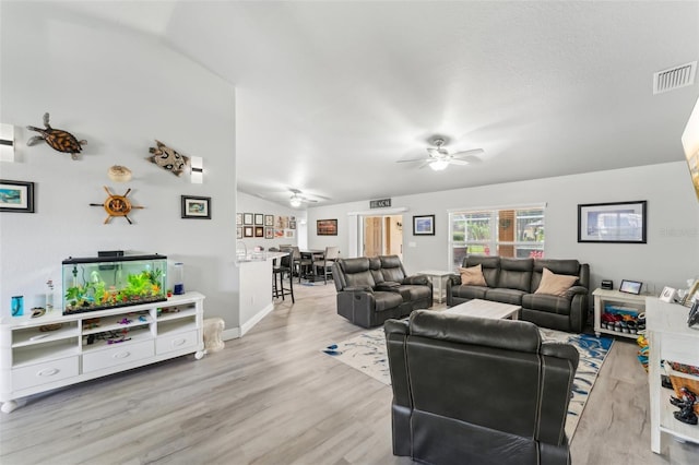 living area featuring lofted ceiling, visible vents, baseboards, a ceiling fan, and light wood-type flooring