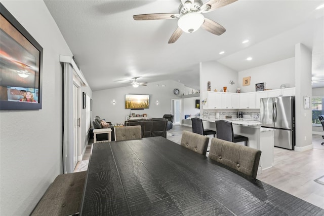 dining room with light wood-style floors, vaulted ceiling, baseboards, and a ceiling fan