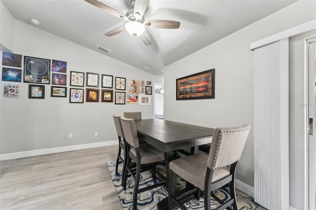 dining room featuring visible vents, light wood-style floors, a ceiling fan, vaulted ceiling, and baseboards