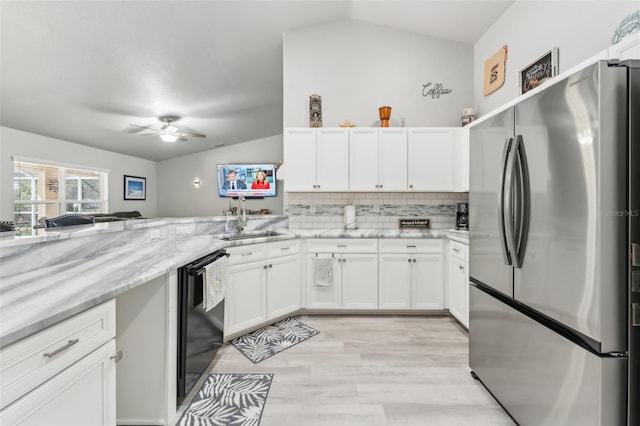 kitchen featuring lofted ceiling, freestanding refrigerator, white cabinetry, a sink, and dishwasher