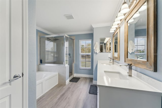 bathroom with a garden tub, ornamental molding, a sink, a shower stall, and wood finished floors