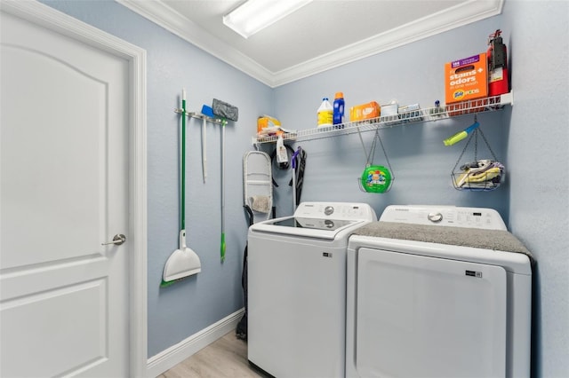 laundry area featuring washing machine and dryer, laundry area, baseboards, light wood finished floors, and crown molding