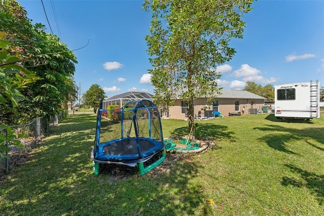 view of playground featuring a trampoline, fence, and a lawn