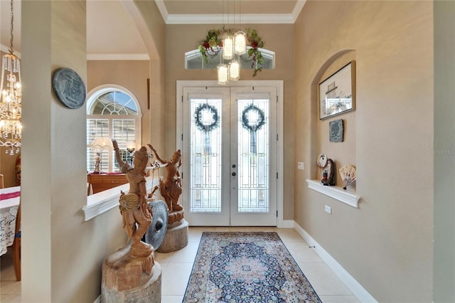 foyer with ornamental molding, tile patterned flooring, french doors, and baseboards