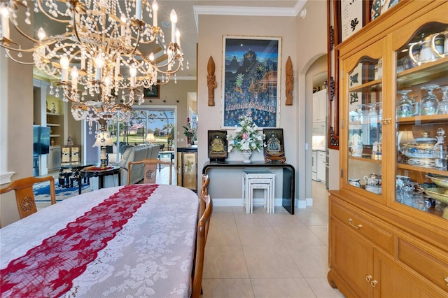 dining space with arched walkways, crown molding, light tile patterned floors, a chandelier, and baseboards