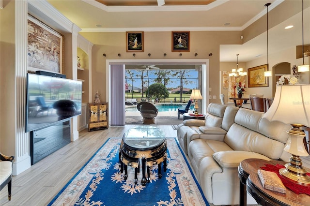 living room with light wood-style floors, a chandelier, and crown molding