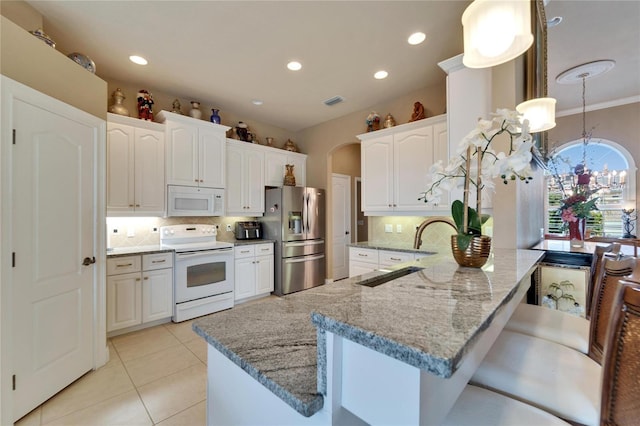 kitchen featuring light stone counters, arched walkways, white cabinetry, a sink, and white appliances