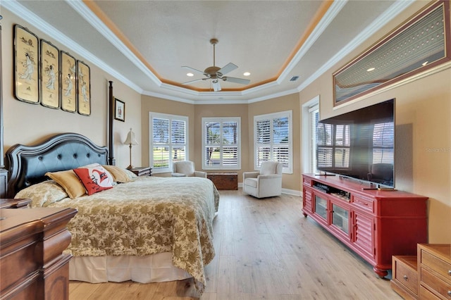 bedroom with baseboards, a raised ceiling, light wood-style flooring, and crown molding