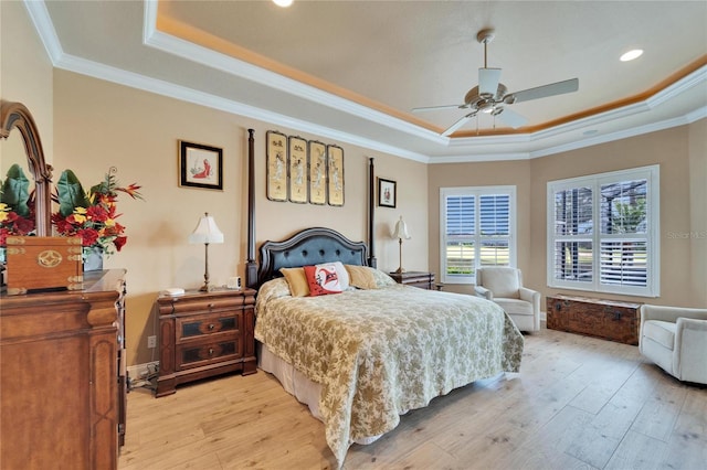 bedroom with light wood-type flooring, a raised ceiling, and crown molding