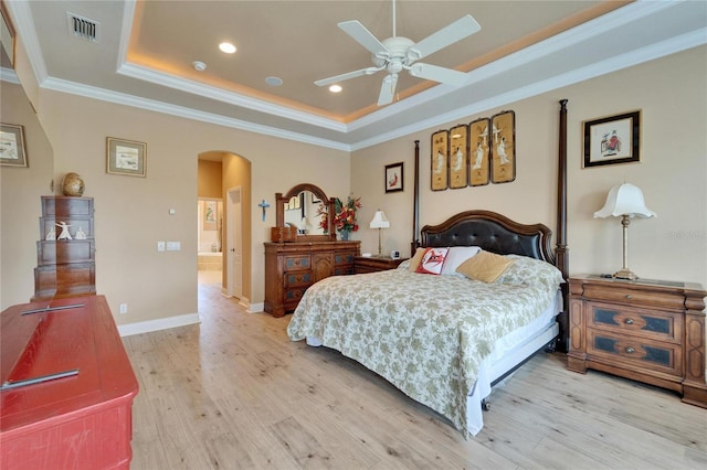 bedroom featuring visible vents, a raised ceiling, arched walkways, light wood-style flooring, and crown molding