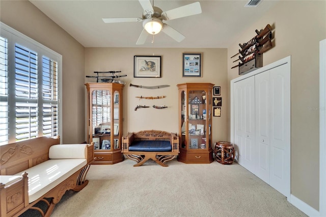 living area with ceiling fan and carpet flooring