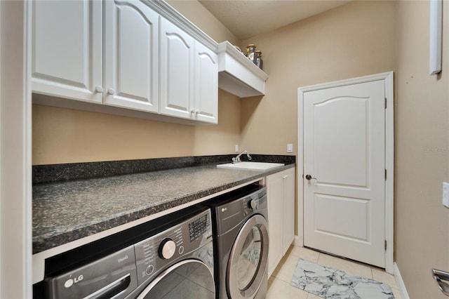 washroom featuring cabinet space, light tile patterned floors, baseboards, washer and dryer, and a sink