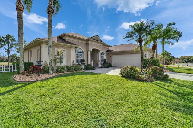 mediterranean / spanish house with a front yard, an attached garage, and stucco siding