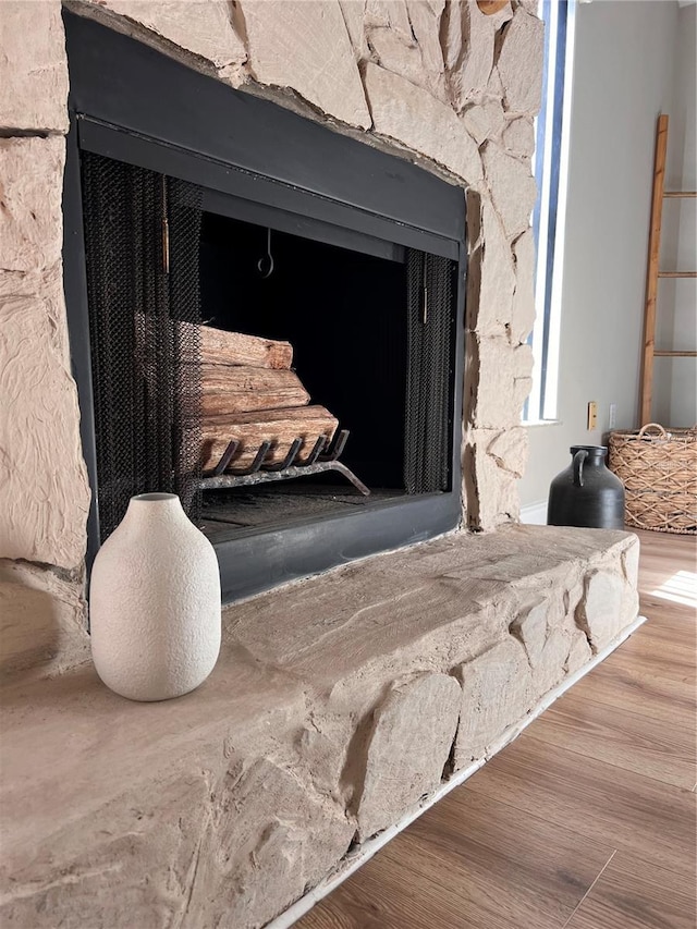 interior details featuring wood finished floors and a stone fireplace