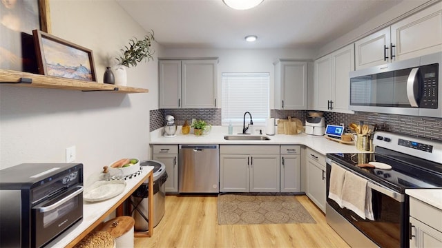 kitchen featuring appliances with stainless steel finishes, open shelves, a sink, and light countertops