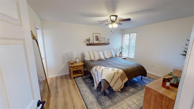 bedroom with baseboards, ceiling fan, and light wood-style floors