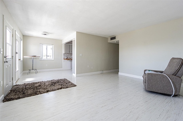 living area with light wood finished floors, visible vents, and baseboards