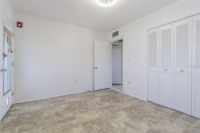 unfurnished bedroom with a closet, stone finish floor, visible vents, and baseboards