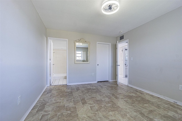 spare room with a textured ceiling, stone finish flooring, visible vents, and baseboards