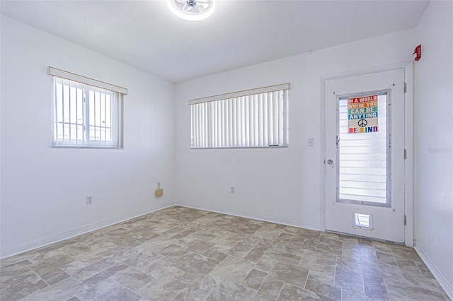 unfurnished room featuring stone finish floor and baseboards