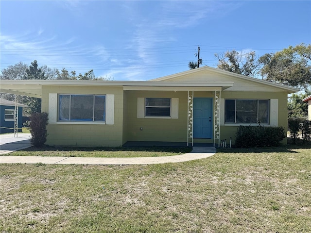 view of front of property with concrete block siding, an attached carport, and a front yard