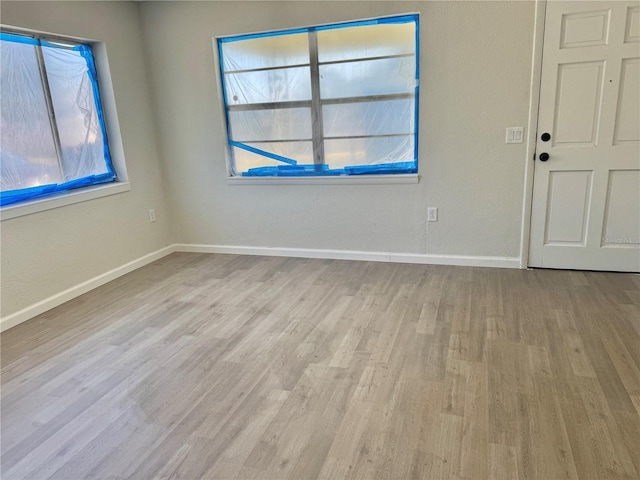 empty room featuring baseboards, wood finished floors, and a healthy amount of sunlight