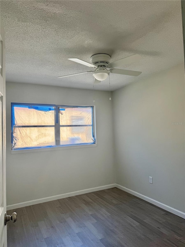 empty room with a textured ceiling, wood finished floors, a ceiling fan, and baseboards