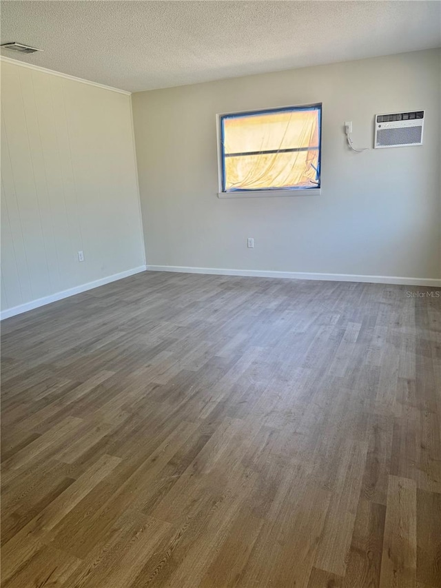 unfurnished room with a textured ceiling, dark wood-style flooring, and baseboards