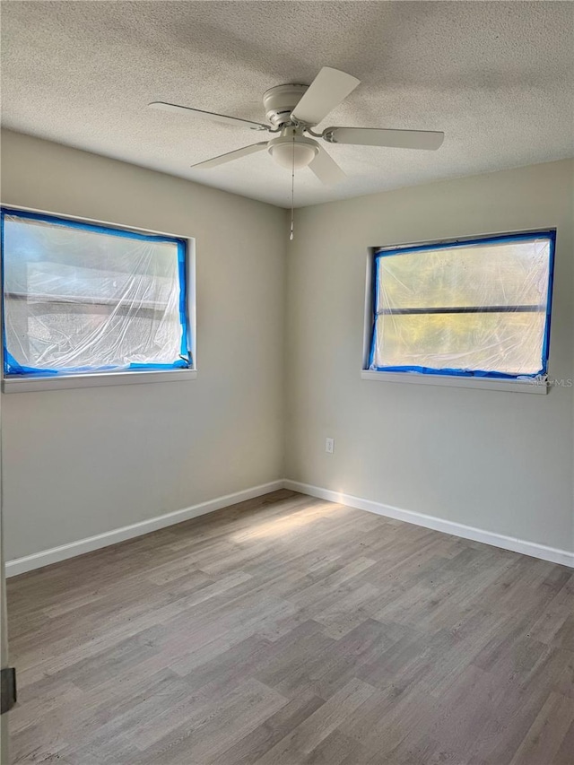 spare room featuring a ceiling fan, a textured ceiling, baseboards, and wood finished floors