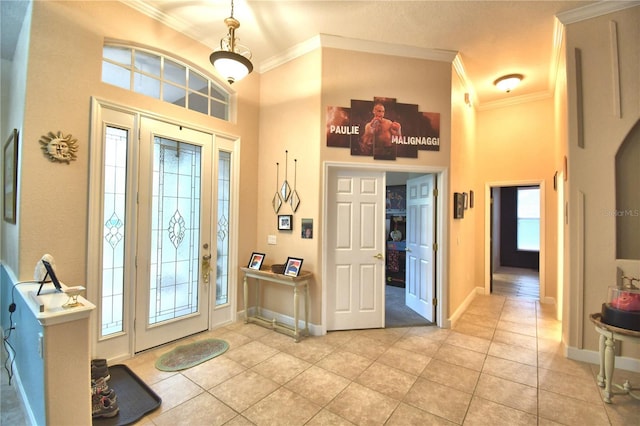 foyer with ornamental molding, a towering ceiling, baseboards, and light tile patterned floors