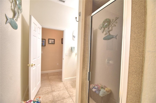 bathroom featuring a stall shower, tile patterned flooring, and baseboards