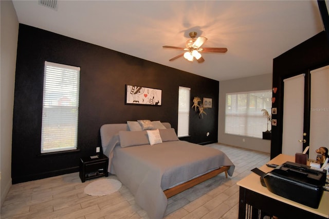 bedroom with light wood-style floors, visible vents, and a ceiling fan