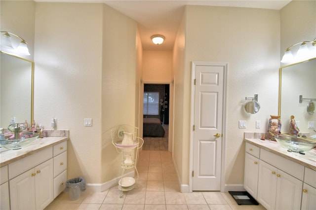 bathroom featuring baseboards, two vanities, a sink, and tile patterned floors