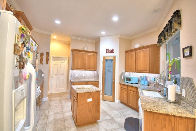 kitchen with white fridge with ice dispenser, a kitchen island, a sink, and crown molding