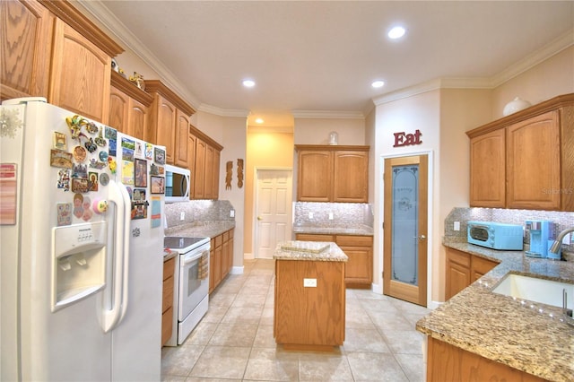 kitchen featuring a center island, crown molding, a sink, light stone countertops, and white appliances