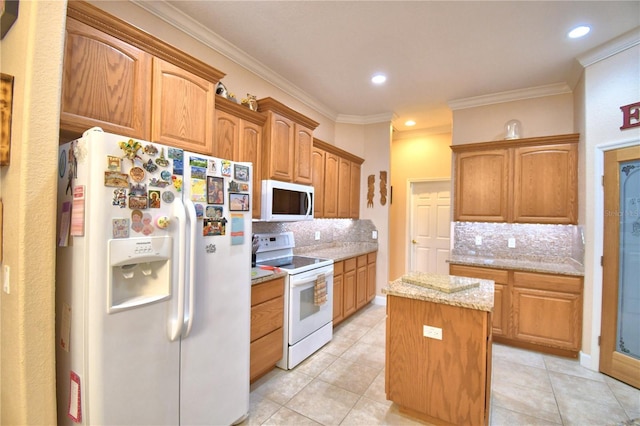 kitchen with light stone counters, a center island, white appliances, and ornamental molding