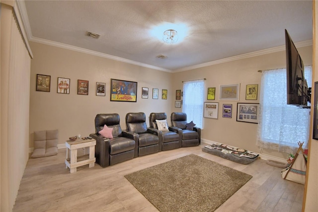 cinema featuring baseboards, visible vents, ornamental molding, wood finished floors, and a textured ceiling