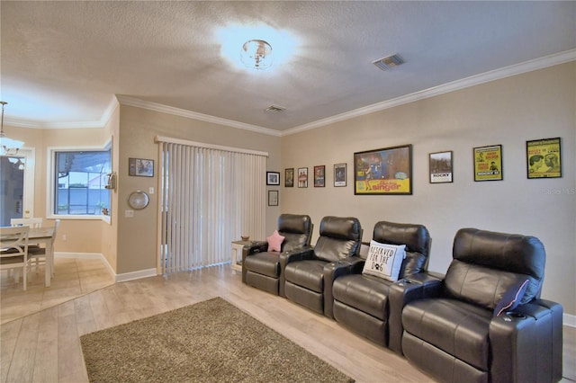 cinema with a textured ceiling, visible vents, baseboards, ornamental molding, and light wood finished floors