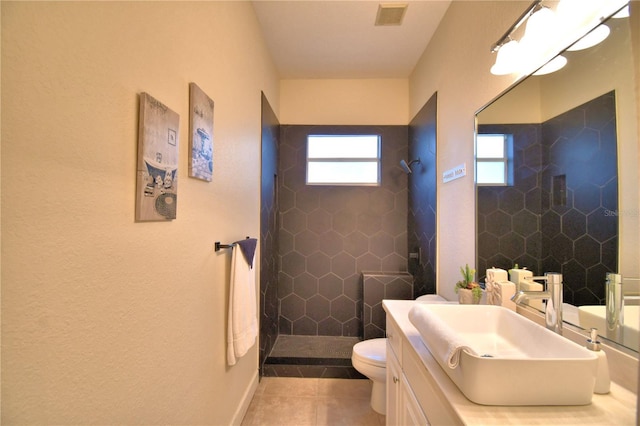 full bathroom featuring tiled shower, vanity, visible vents, and tile patterned floors