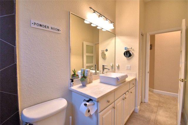 bathroom featuring a textured wall, vanity, toilet, and tile patterned floors