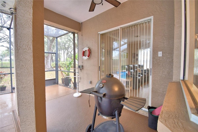 workout room with a textured wall, a sunroom, and a ceiling fan