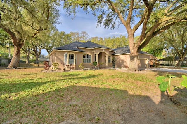 view of front facade with an attached garage, fence, a front lawn, and stucco siding