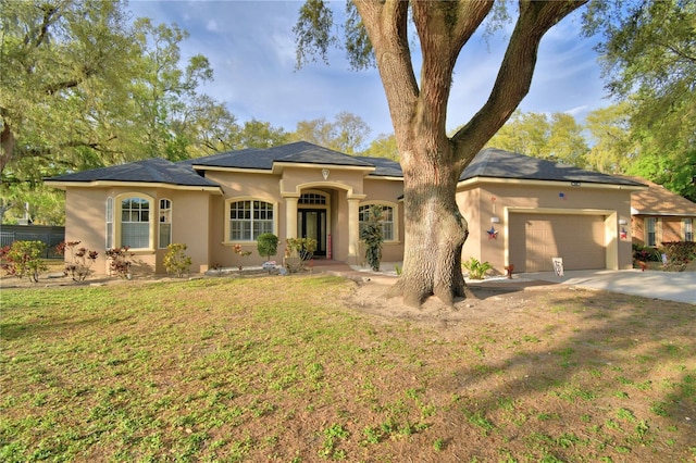 view of front facade featuring driveway, stucco siding, an attached garage, and a front yard