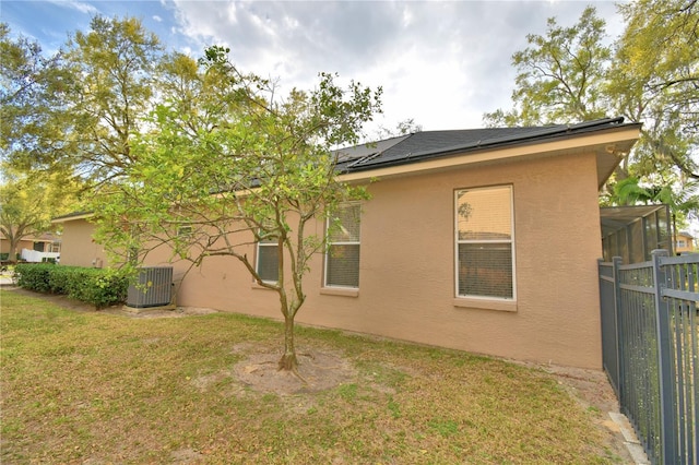 back of property with fence, a lawn, central AC, and stucco siding