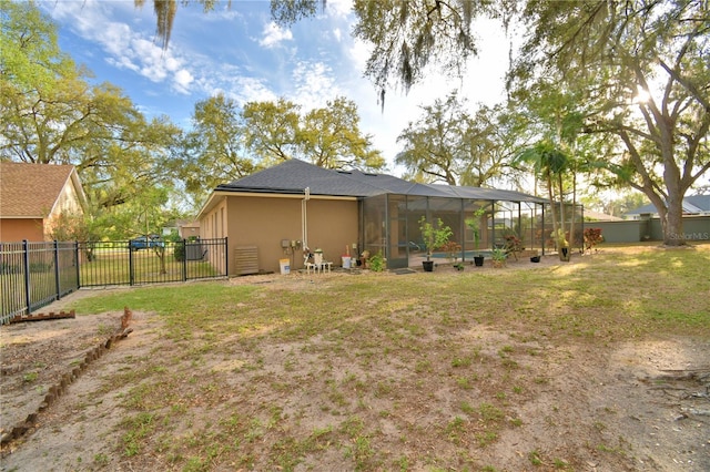 rear view of house with a lawn, fence private yard, a lanai, and stucco siding