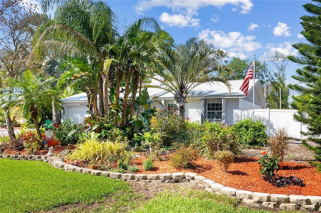 view of front facade featuring metal roof, an attached garage, and fence