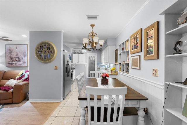 dining space featuring light tile patterned floors, visible vents, a wainscoted wall, an inviting chandelier, and crown molding