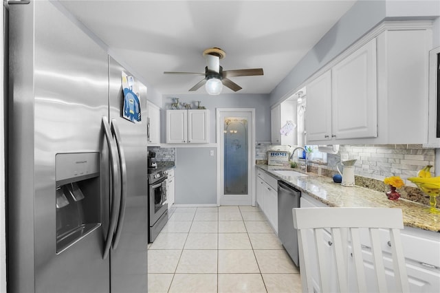 kitchen with light tile patterned floors, appliances with stainless steel finishes, a sink, and white cabinetry