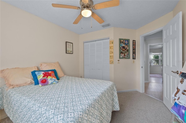 carpeted bedroom featuring a closet, visible vents, ceiling fan, a textured ceiling, and baseboards