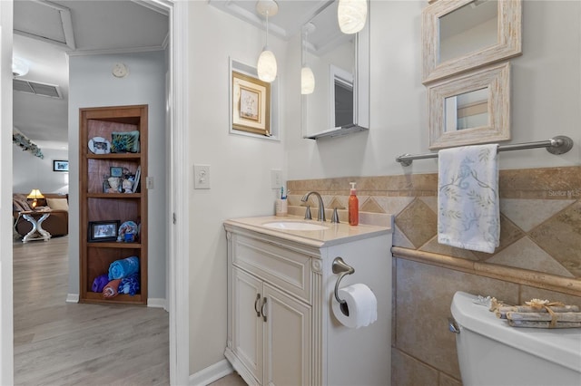 bathroom with visible vents, toilet, wood finished floors, crown molding, and vanity